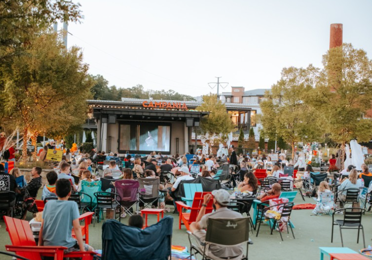 Outdoor movie night with crowd watching a film on a large screen
