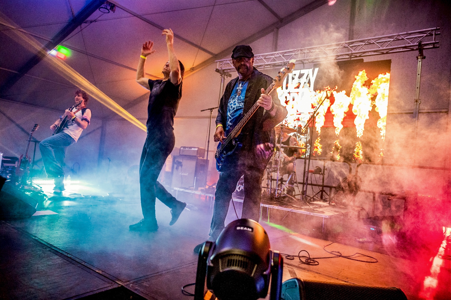 Live band performing on a fog-filled festival stage with pyrotechnics